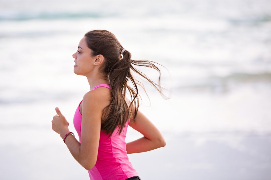 Woman in pink running along the beach