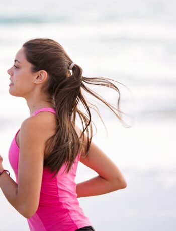 Woman in pink running along the beach