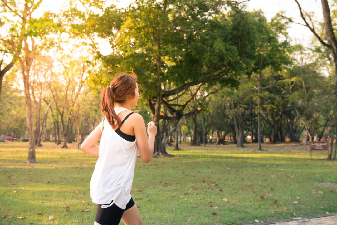 woman wearing white shirt and black shorts running through park