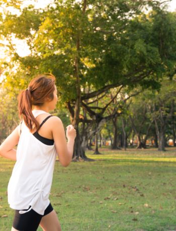 woman wearing white shirt and black shorts running through park
