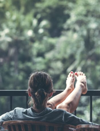 woman relaxing on balcony looking out at trees