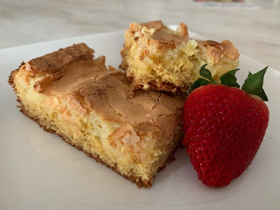 Ooey Gooey Butter Cake on white plate with strawberry
