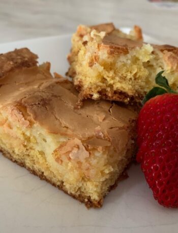 Ooey Gooey Butter Cake on white plate with strawberry