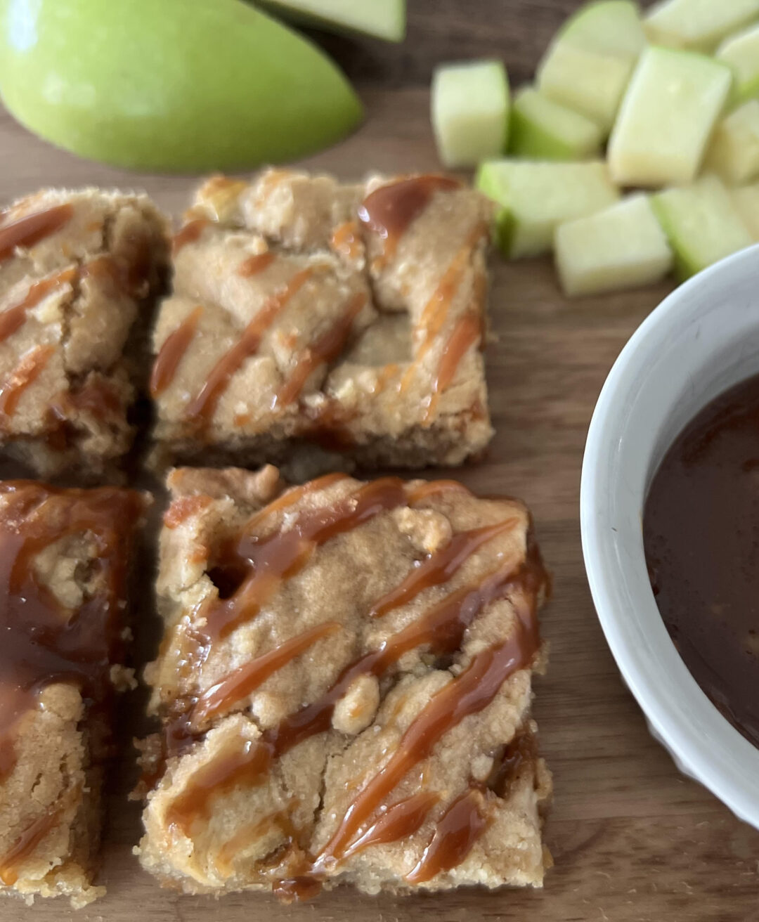 Caramel Apple Cookie Bars with Granny Smith apple slices on a wood cutting board.