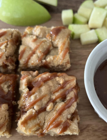 Caramel Apple Cookie Bars with Granny Smith apple slices on a wood cutting board.