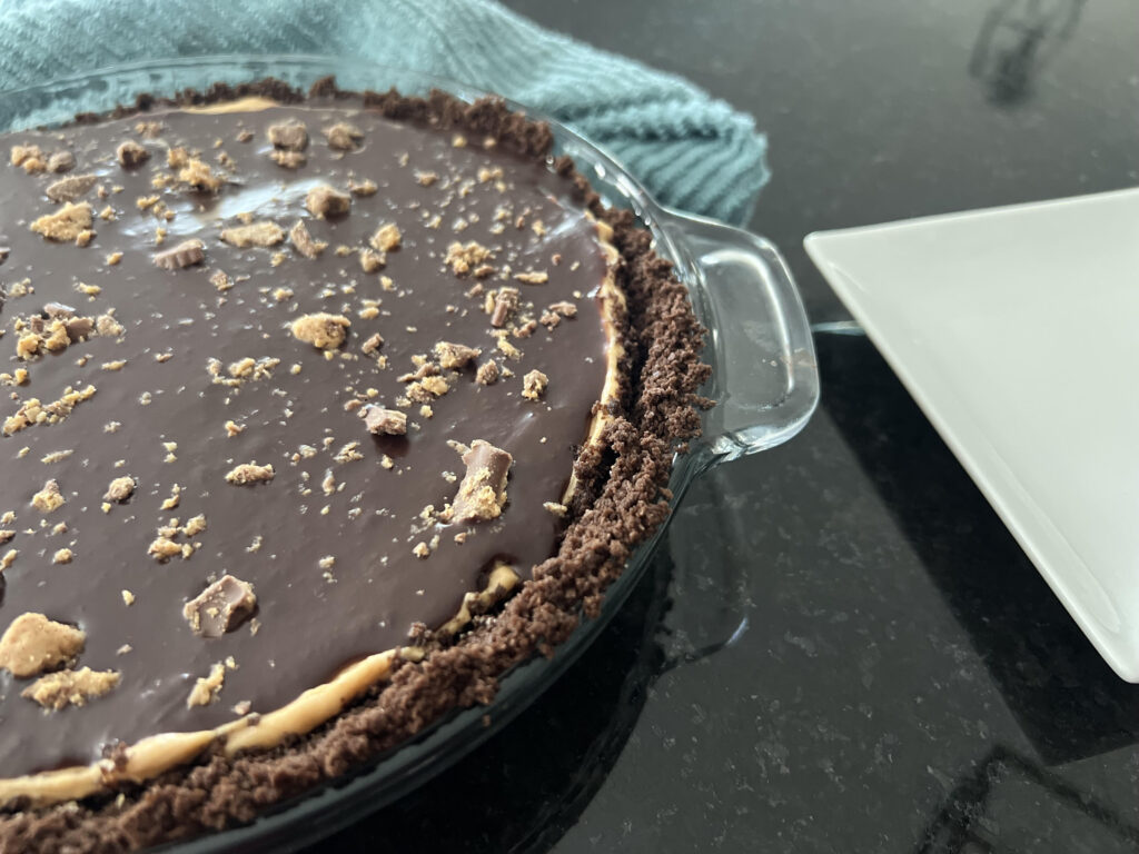 Half of a Peanut butter Cream Pie in glass pie pan.