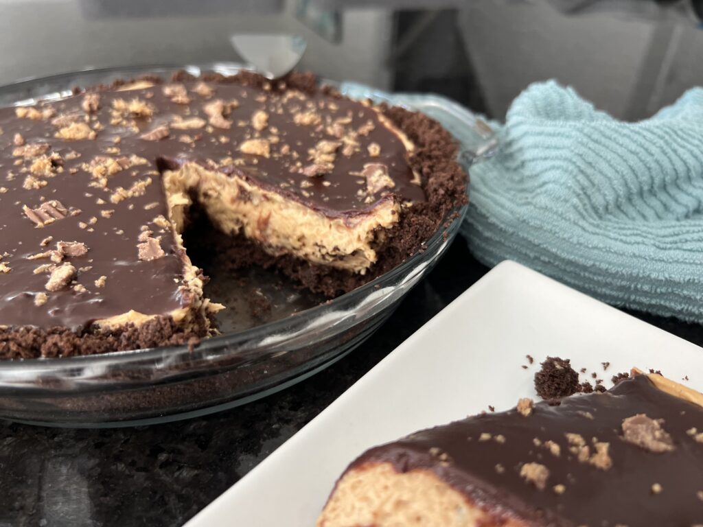 Sliced view of Peanut Butter Cream Pie with slice on a white plate.